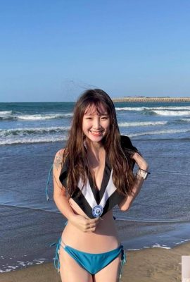 Gadis cantik mengambil foto kelulusan di tengah angin dingin di pantai